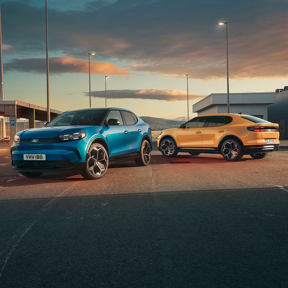 Ford Capri in Blau und in Gelb. Parken bei Sonnenuntergang auf einem Parkplatz.