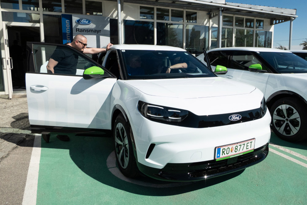 Weißer Ford Ford Capri der ÖkoFEN-Mitarbeiterflotte mit grünen Akzenten geparkt vor einem Ford Autohaus.