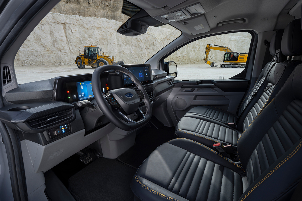 Ford E-Transit Custom Innenraum mit Blick auf Fahrer- und Beifahrerseite. Das Fahrzeug parkt in einem Steinbruch. 