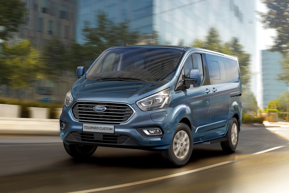 Ford Tourneo Custom in Blau. Dreiviertelansicht, fährt durch die Stadt