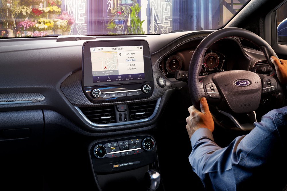Innenraum eines Ford Puma, Hände am Lenkrad und großes Touchscreen-Display.
