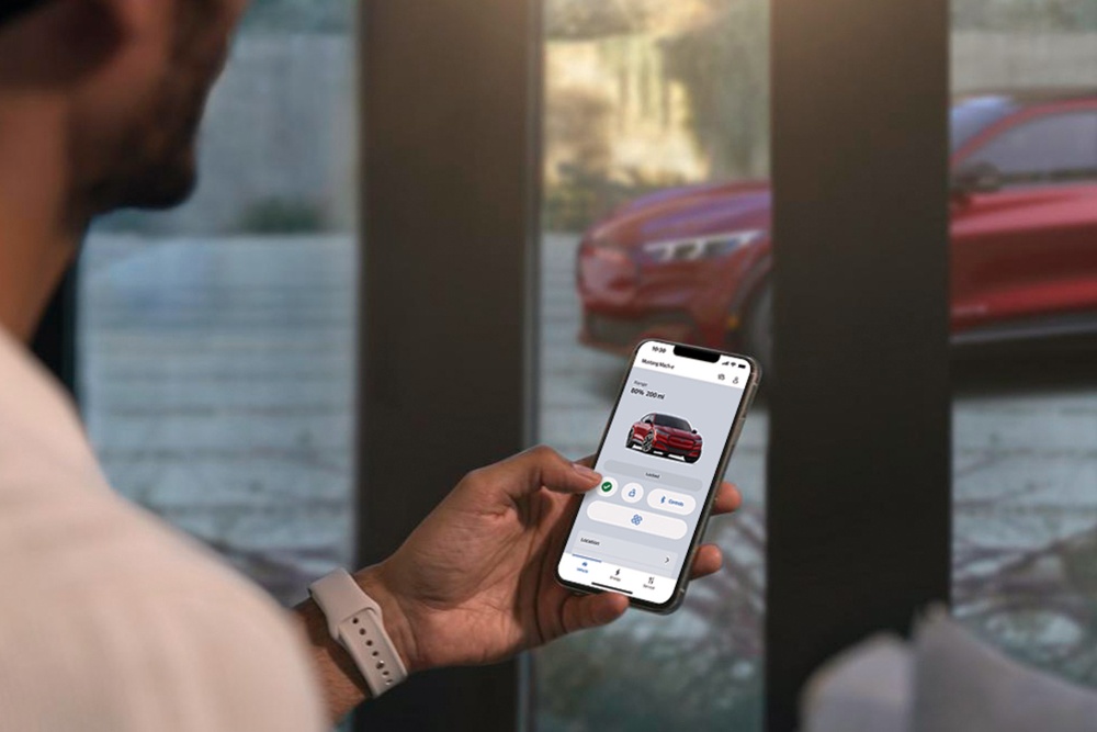 Hand hält ein Smartphone mit geöffneter Ford App, die eine Grafik eines Ford Fahrzeugs zeigt.