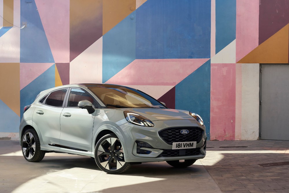 Ford Puma in Grau. Dreiviertelansicht, parkt vor einer bunt bemalten Wand. 