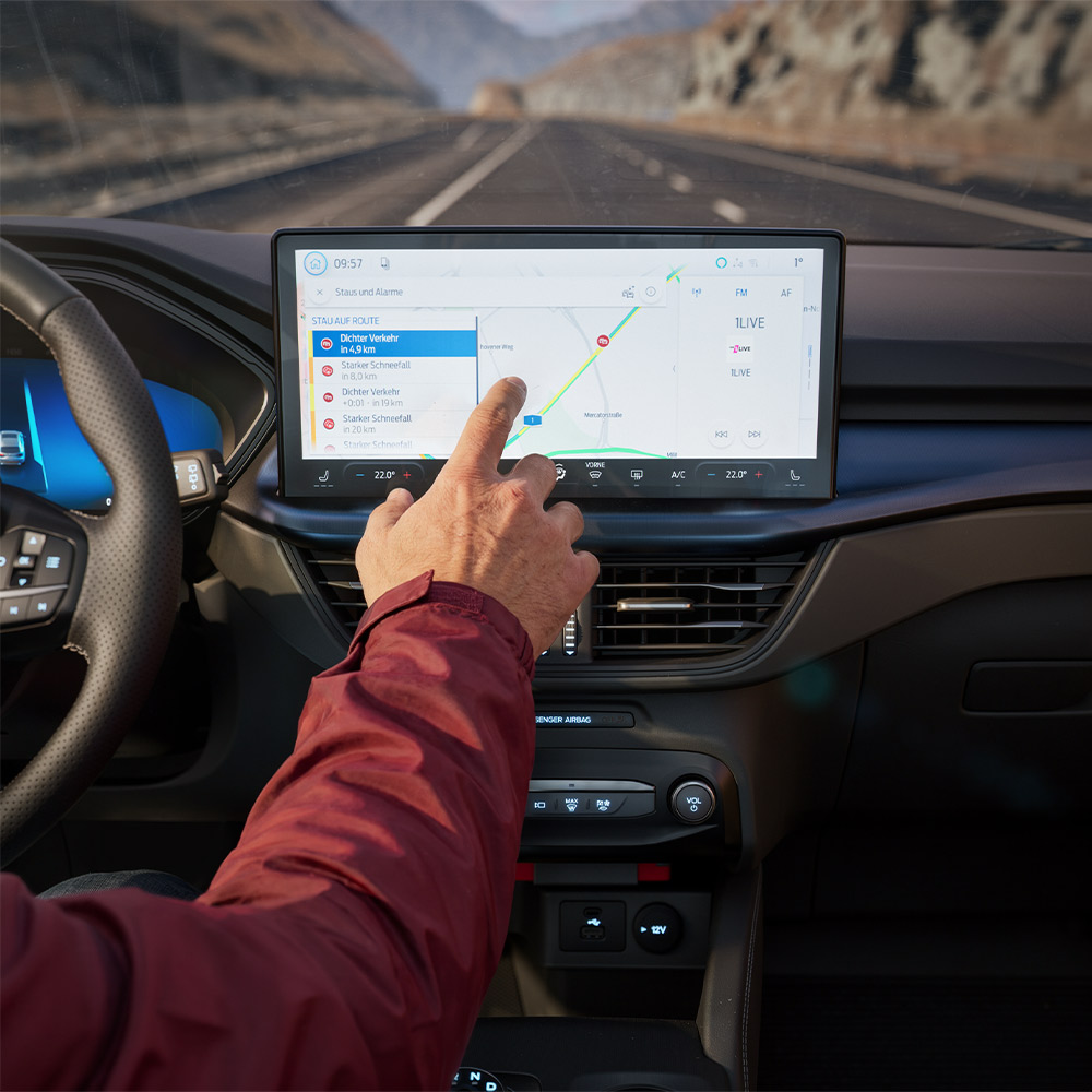 Ein Fahrer bedient Connected-Navigation auf dem Touchscreen im modernen Cockpit einer Ford BlueCruise Edition.