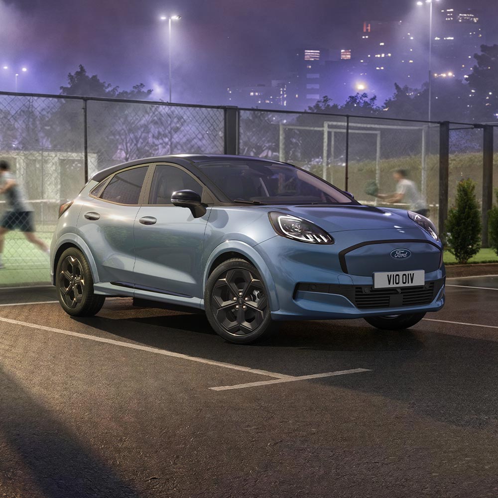 Ford Puma Gen-E BlueCruise Edition in Blau. Dreiviertelansicht, vor einem Padel-Court.
