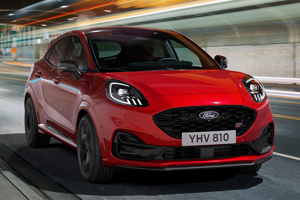 Ford Puma in Rot. Frontansicht, fahrend durch die Stadt bei Nacht.