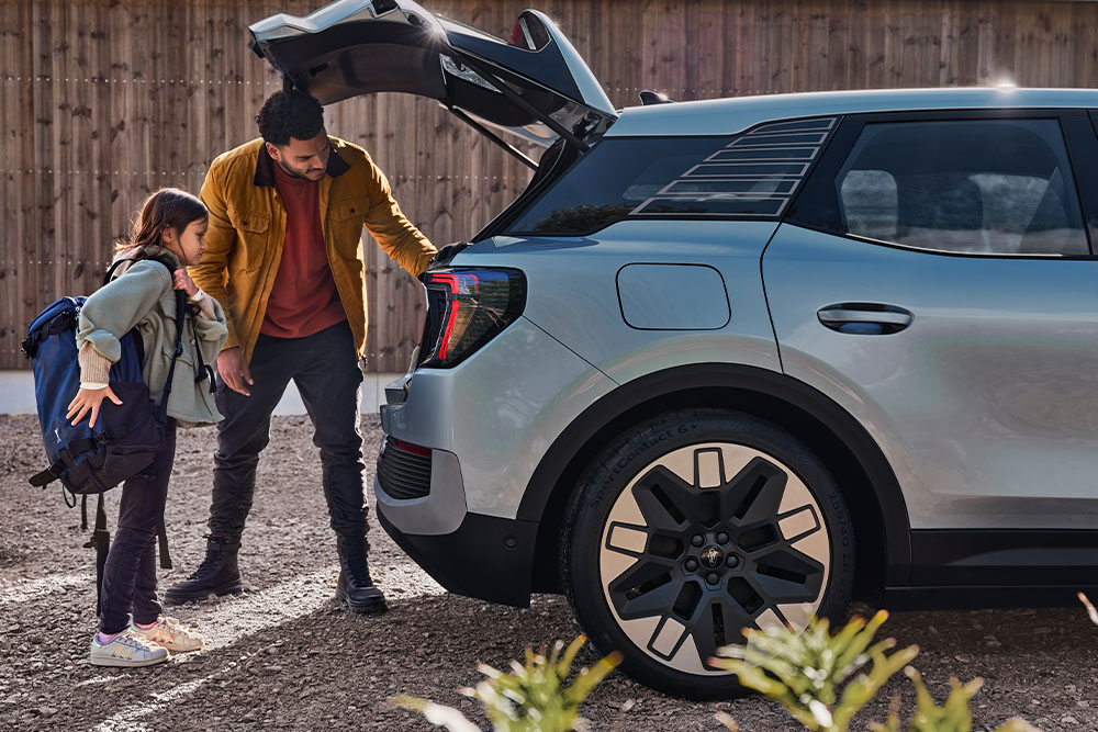 Eine Person und ein Kind beladen den Kofferraum eines blauen Ford Explorer.