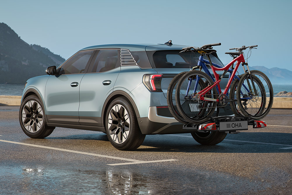 Ford Explorer in Blau. Heckansicht, fährt auf einer Autobahn mit Bäumen und Felsen entlang der Fahrbahn.
