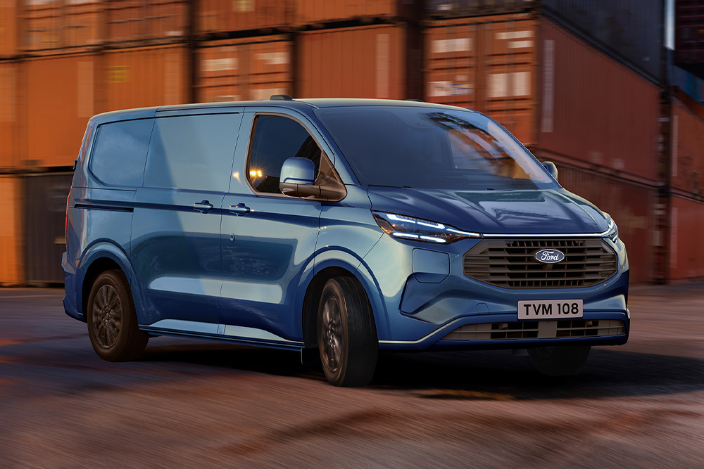Ford Transit Custom in Blau fährt an Containern vorbei.