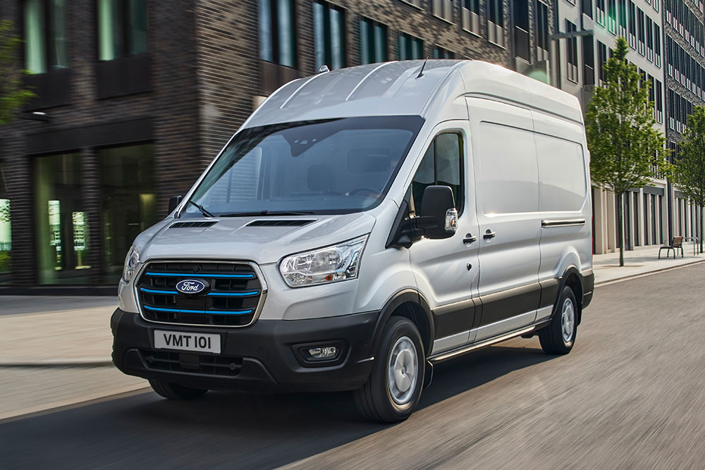 Ford E-Transit Kastenwagen in Silber. Dreiviertelansicht, fährt durch die Stadt.