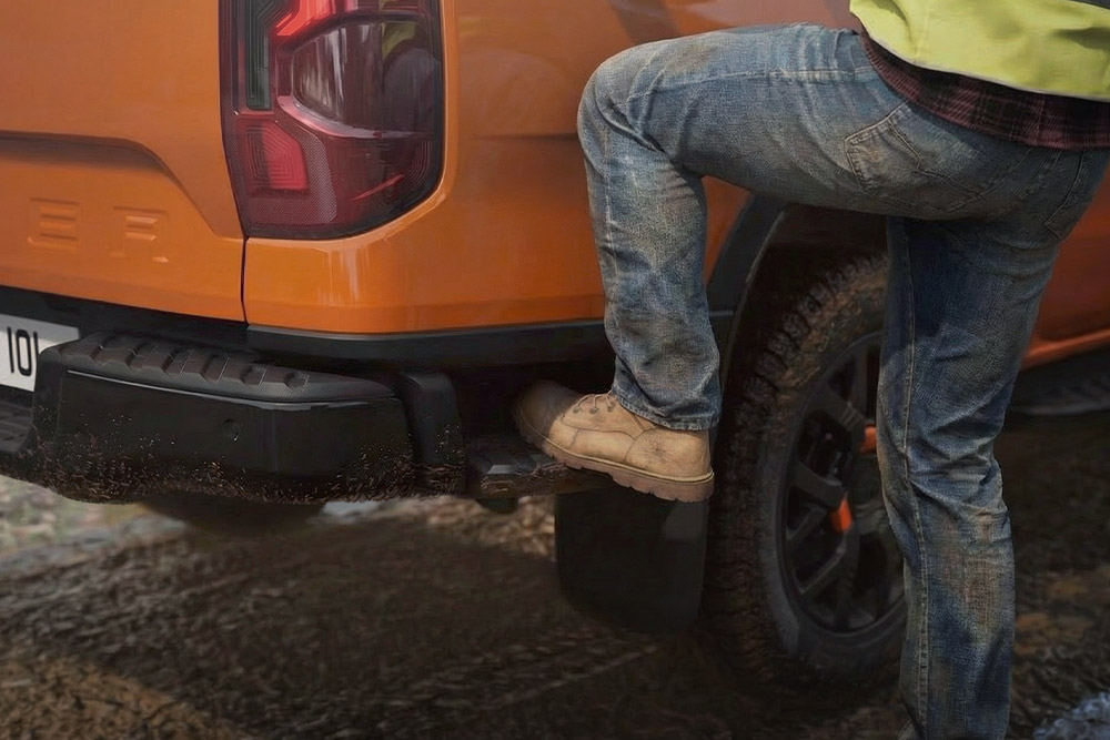Ford Ranger Wildtrak in Orange. Ansicht der integrierten Hecktrittstufe am hinteren Stoßfänger.