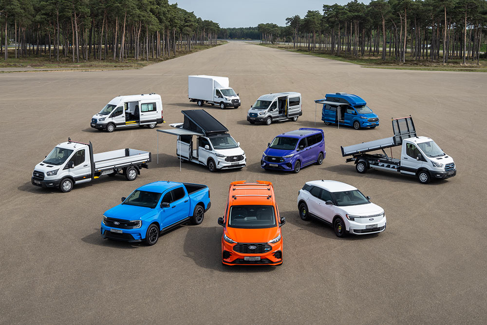 10 Ford Nutzfahrzeuge aus der Vogelperspektive stehen nebeneinander auf einer Fahrbahn.