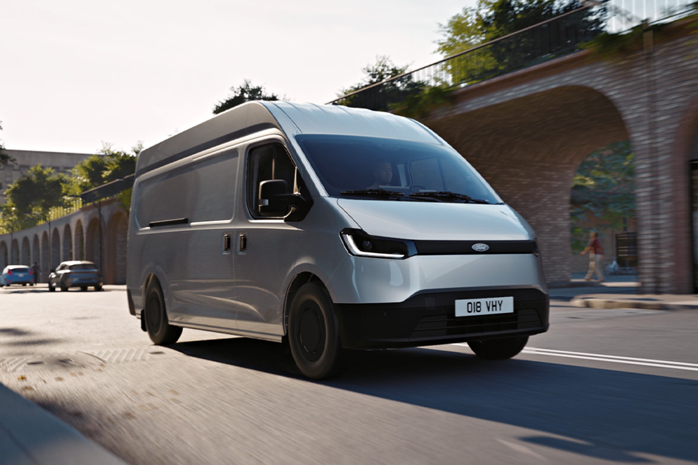 Ford Transit City in Silber. Dreiviertelansicht, fährt eine Straße entlang.