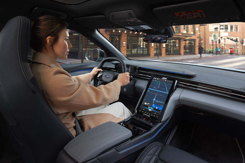 Eine Person fährt in einem Ford. Auf dem Touchscreen ist die Navigation zu sehen.