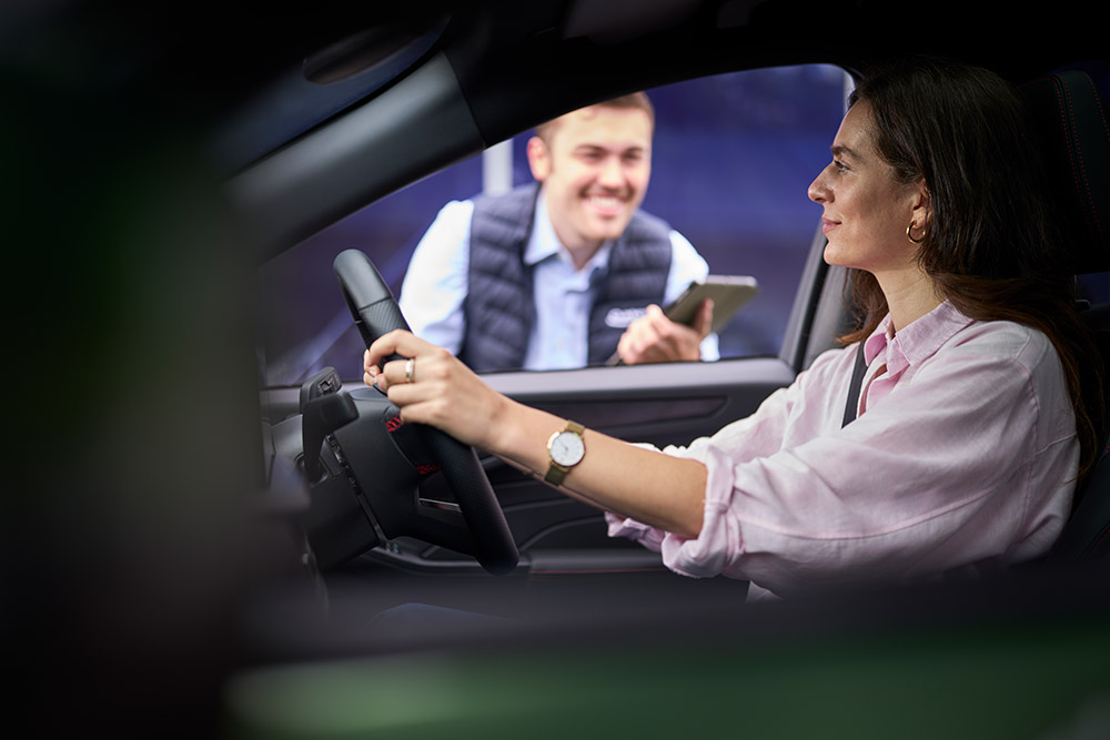Eine Person auf dem Fahrersitz eines Ford-Fahrzeugs mit geöffnetem Fenster.