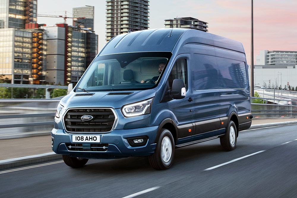 Ford E-Transit in Blau. Dreiviertelansicht, fährt bei Sonnenuntergang auf einer Autobahn.