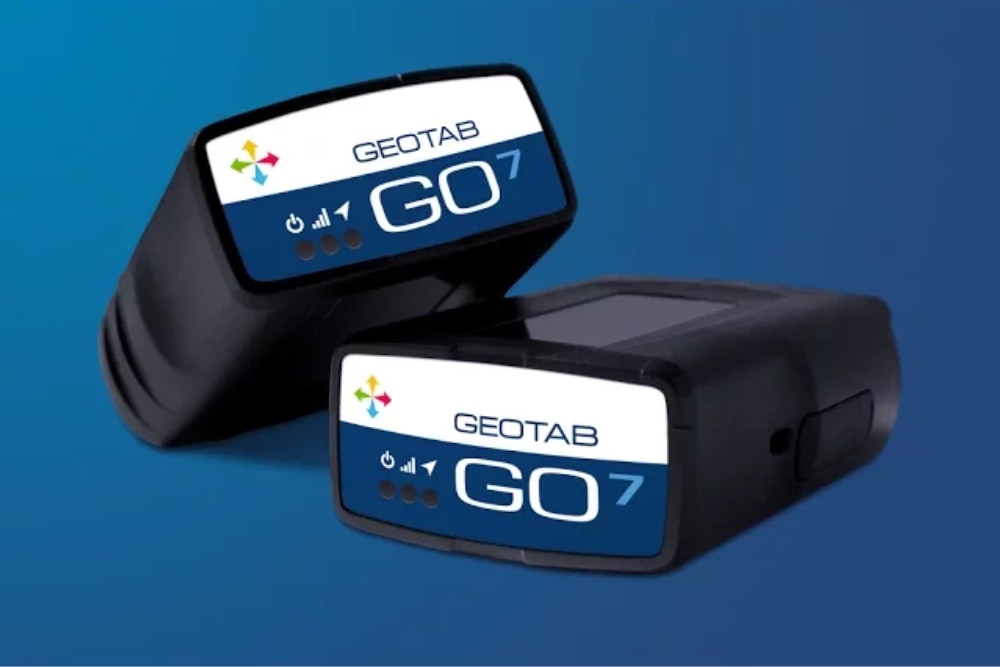 Zwei Geotab GO7 Telematics-Geräte zur Fahrzeugdatenerfassung vor einem blauen Hintergrund.